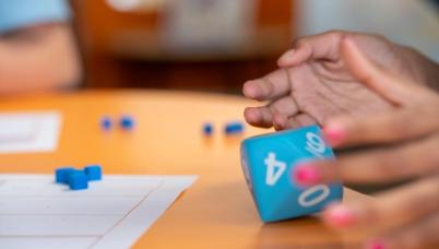 A student rolls a fist-sized 10 sided die