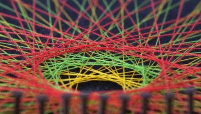 Extreme close up of the centre of a piece of string art of multiple colours, aligned on nails