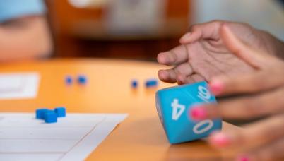 A student rolls a fist-sized 10 sided die