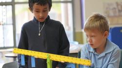 2 students examine a balancing tool in some confusion