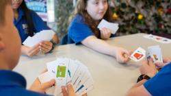 Four student players in a square play cards with the printed Robots
