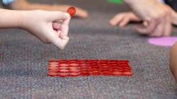 Students lay out red counters on the floor