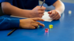 Students at a desk with paper, pens, and standard cube dice