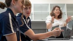 students in foreground, teacher in background