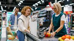 Cashier scanning groceries at supermarket checkout for a queue of customers
